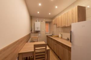a kitchen with wooden cabinets and a table and a refrigerator at Apartamenty ZYGFRYD 28C/3/1 in Bystrzyca Kłodzka