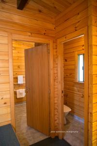 een houten badkamer met een toilet en een deur bij Paparoa Park Motel in Punakaiki