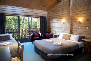 a hotel room with two beds and a balcony at Paparoa Park Motel in Punakaiki