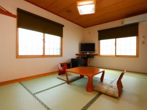 uma sala de estar com uma mesa e duas janelas em Takanoya em Yuzawa