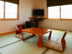 uma sala de estar com uma mesa e uma televisão em Takanoya em Yuzawa