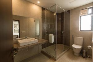 a bathroom with a sink and a toilet and a shower at Park Suites in Kolkata