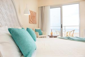 ein Schlafzimmer mit einem Bett mit blauen Kissen in der Unterkunft Pegasos Deluxe Beach Hotel in Faliraki