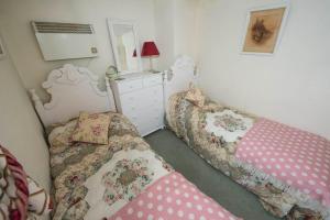 a bedroom with two beds and a dresser and a mirror at Pebble Cottage in Holt