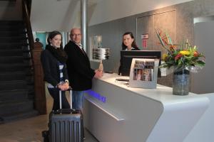 3 Personen stehen an der Rezeption mit Koffer in der Unterkunft Hotel Schweriner Hof in Stralsund