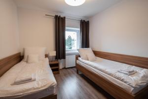 two beds in a room with a window at Apartamenty ZYGFRYD 28C/3/3 in Bystrzyca Kłodzka