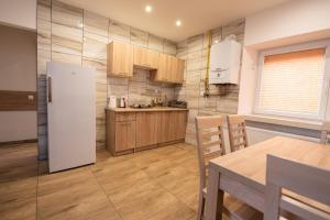 a kitchen with a white refrigerator and wooden cabinets at Apartamenty ZYGFRYD 28C 3 6 in Bystrzyca Kłodzka