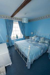 a blue bedroom with a bed and a window at Delphinium Cottage in Holt