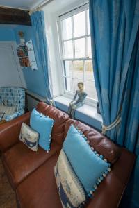 a brown leather couch sitting in front of a window at Delphinium Cottage in Holt