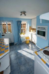 a kitchen with blue walls and white appliances at Delphinium Cottage in Holt