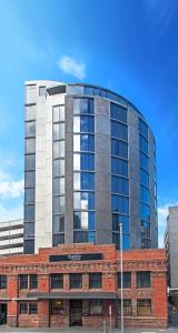 a tall glass building in front of a red brick building at Mantra Collins Hotel in Hobart