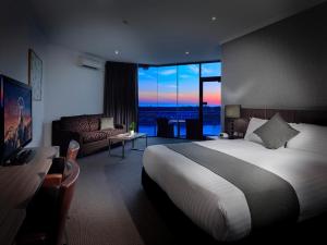 um quarto de hotel com uma cama e uma sala de estar em Lakes Hotel em Adelaide