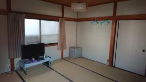 a room with a tv and a table in a room at Guesthouse Kumano in Tanabe