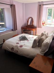 een slaapkamer met een bed, een tafel en 2 ramen bij Ashley Croft in Skipton