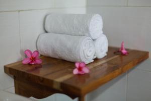 a pile of towels on a wooden table with pink flowers at Mamaras Guest House in Nusa Penida +128 photos