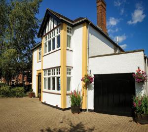 ein weißes und gelbes Haus mit Garage in der Unterkunft Sandfield Guest House in Oxford
