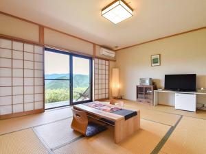ein Wohnzimmer mit einem großen Fenster und einem TV in der Unterkunft Kirinosato Takahara in Tanabe