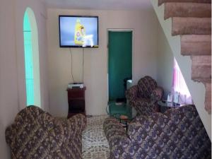 a living room with two chairs and a flat screen tv at Reggae Moon Guesthouse in Falmouth