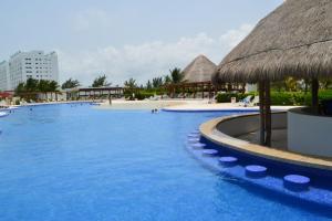 uma grande piscina com um guarda-chuva de palha em Cancun Amara em Cancún