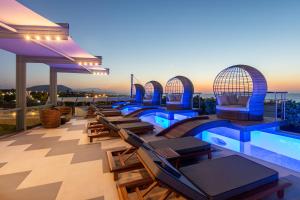 a pool on the roof of a building with chairs at Onira Suite Dreams in Hersonissos +144 photos