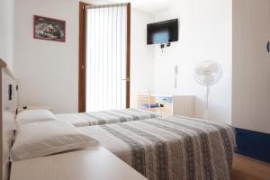 a hotel room with two beds and a flat screen tv at B&B La Villetta in Breno