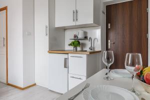 a kitchen with white cabinets and a table with wine glasses at Apartament w centrum Starówki Old Town in Gdańsk