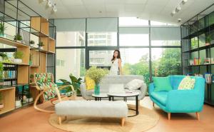 une femme debout dans une pièce avec des chaises et une table dans l'établissement Techgarden Workstay Dorm - Coworking Space, à Hanoï