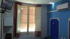 a room with a window and a blue wall at Hostal Porta de Ferro in Sant Boi del Llobregat