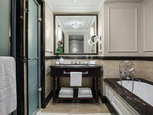 a bathroom with a tub and a sink and a mirror at The Langham London in London