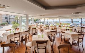 un restaurante con mesas y sillas blancas y ventanas en Miramare Hotel en Rapallo