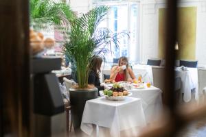 two women sitting at tables in a restaurant at Parkhotel Laurin in Bolzano