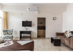 - un salon avec un canapé et une télévision dans l'établissement Olive Service Apartments - Koramangala, à Bangalore