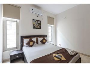 - une chambre avec un grand lit et 2 fenêtres dans l'établissement Olive Service Apartments - Koramangala, à Bangalore