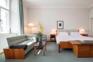 a bedroom with a large bed and a couch at Parkhotel Laurin in Bolzano