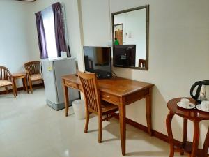 Habitación con escritorio, TV y espejo. en สตาร์ รีสอร์ท (สี่แยก จปร) en Nakhon Nayok