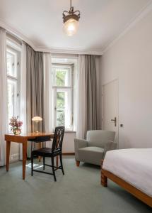 a bedroom with a bed and a desk and a chair at Parkhotel Laurin in Bolzano