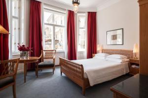 a bedroom with a bed with red curtains and a table at Parkhotel Laurin in Bolzano