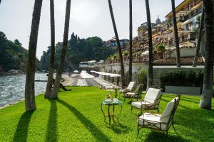 a group of chairs and tables on a lawn next to the water at Atlantis Bay - VRetreats in Taormina