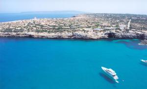 a boat in the water next to an island at Hotel Club Sunway Punta Prima in Es Pujols