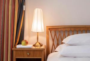a lamp on a table next to a bed with an apple on it at Parkhotel Laurin in Bolzano