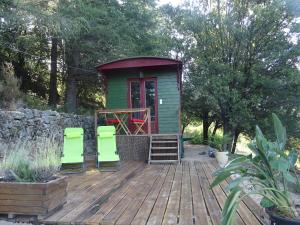 une cabine verte avec deux chaises vertes sur une terrasse en bois dans l'établissement Pura Vida, à Valleraugue