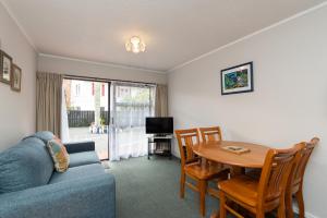 a living room with a blue couch and a table at Edelweiss Motel in Paihia