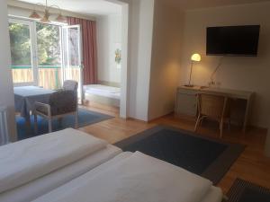 a room with a bed and a table and a television at Comfort Rooms Bruckner in Bad Gastein