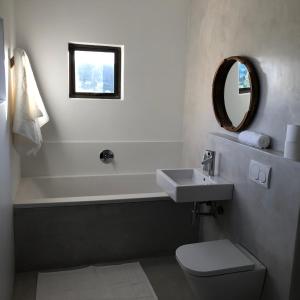 a bathroom with a sink and a toilet and a mirror at The Sanctuary Penthouse in Plettenberg Bay