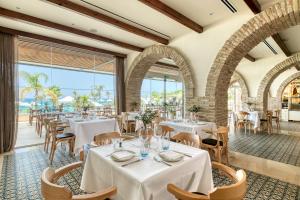 a restaurant with white tables and chairs and large windows at Royal Apollonia by Louis Hotels in Limassol +37 photos