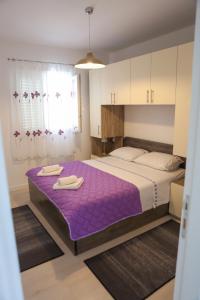 1 dormitorio con 1 cama grande con sábanas moradas en Apartman Diva, en Orebić