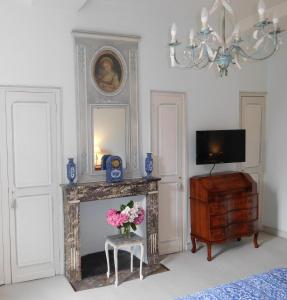 uma sala de estar com lareira e um vaso de flores em Chambres d'hôtes Château de Courcelette em Hem