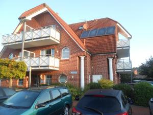 a brick house with cars parked in front of it at Hotel Blischke in Carolinensiel