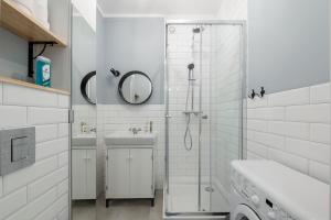 a white bathroom with a shower and a sink at Apartament Ogród Krasińskich in Warsaw