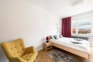 a bedroom with a bed and a chair and a window at Apartament Ogród Krasińskich in Warsaw